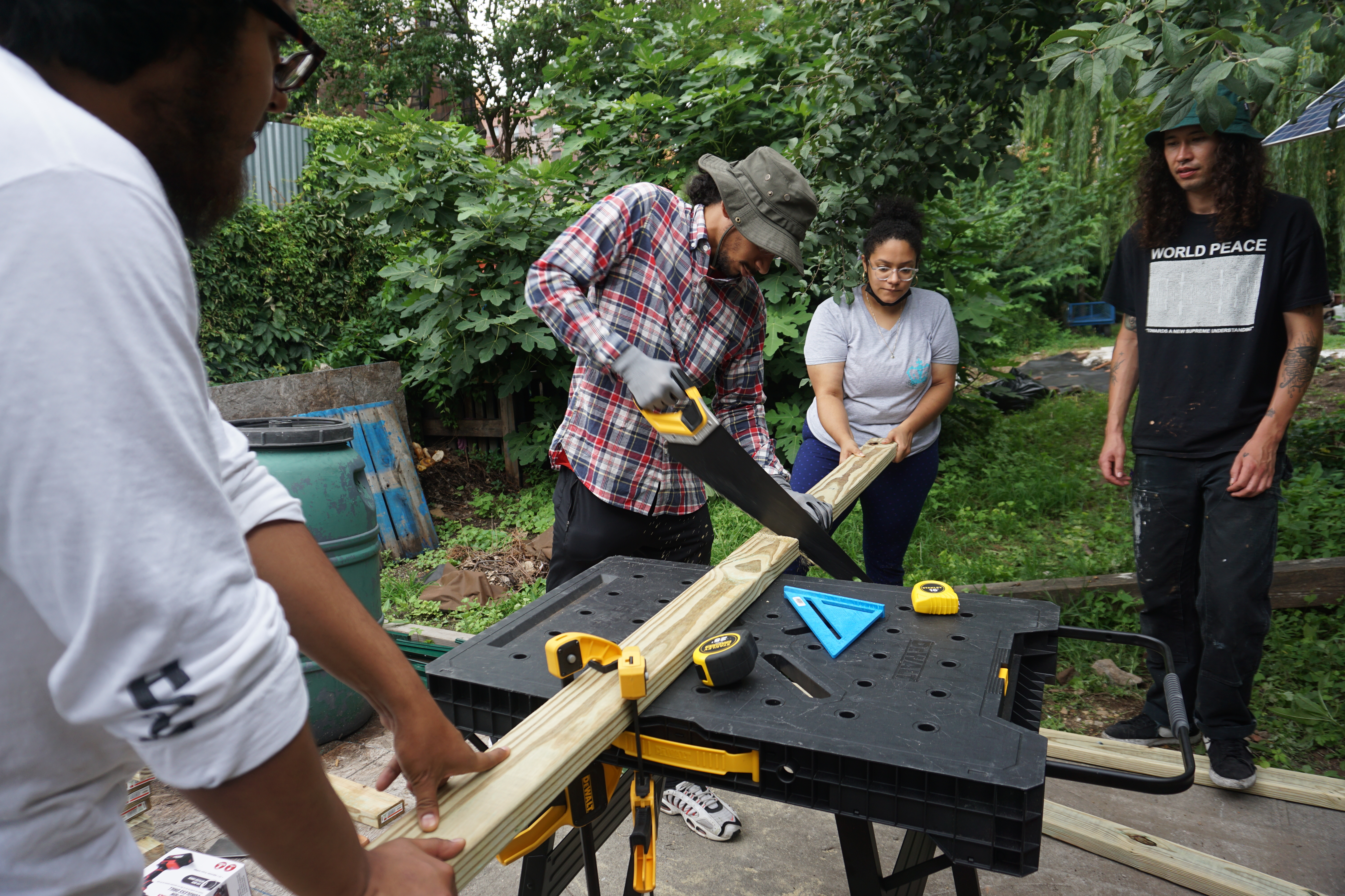 Man sawing wood with friends around and helping him